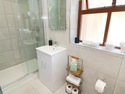 a bathroom with a shower and a sink and a mirror at Sunnybrook Cottage in Clitheroe