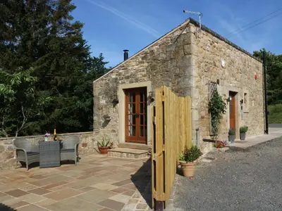 a stone house with a wooden door and a patio at Sunnybrook Cottage in Clitheroe