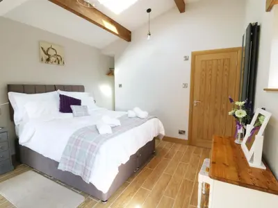 a bedroom with a bed and a wooden floor at Sunnybrook Cottage in Clitheroe