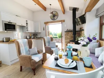 a kitchen and living room with a table and chairs at Sunnybrook Cottage in Clitheroe