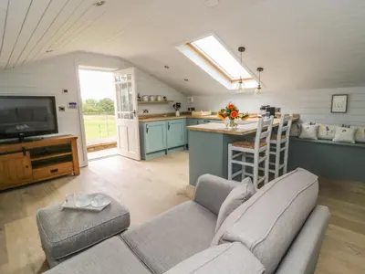 a living room with a couch and a kitchen at Deer Lodge in Blackburn