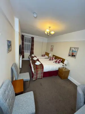a hotel room with a bed and two chairs at Rossdene House in Blackpool