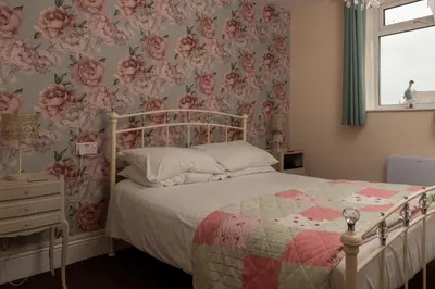 a bedroom with a bed with pink floral wallpaper at The Hurstmere in Blackpool