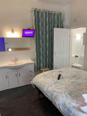 a bedroom with a bed and a sink and a mirror at Danescourt Lodge in Blackpool