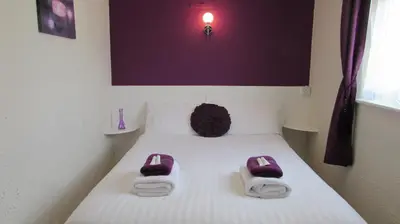 a bed with purple slippers on top of it at Bamford House Hotel in Blackpool