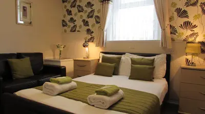 a bedroom with a bed with a couch and a window at Bamford House Hotel in Blackpool