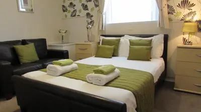 a bedroom with a large bed with green pillows and a couch at Bamford House Hotel in Blackpool