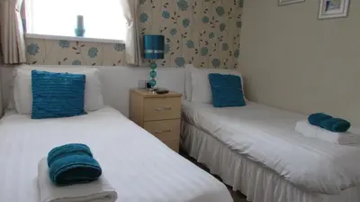 two beds in a room with blue towels on them at Bamford House Hotel in Blackpool