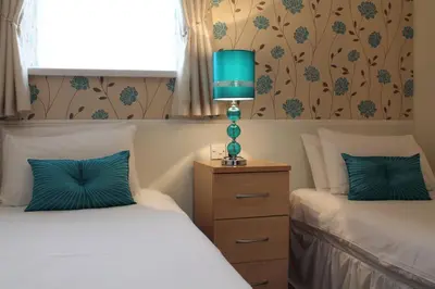 a bedroom with two beds and a lamp on a night stand at Bamford House Hotel in Blackpool