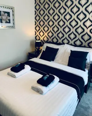 two beds in a hotel room with towels on them at Bamford House Hotel in Blackpool