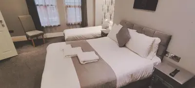 a bedroom with a large bed with white sheets and pillows at The Glebe Hotel in Liverpool