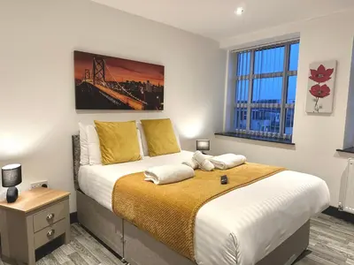 a bedroom with a large bed with yellow pillows at Winter Gardens Service Apartments 2 by Blackpool Service Apartments in Blackpool