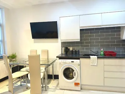 a kitchen with a washing machine and a table with chairs at Winter Gardens Service Apartments 2 by Blackpool Service Apartments in Blackpool