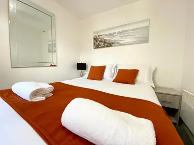 a bedroom with a large white bed with orange pillows at Winter Gardens Service Apartments by Blackpool Service Apartments in Blackpool