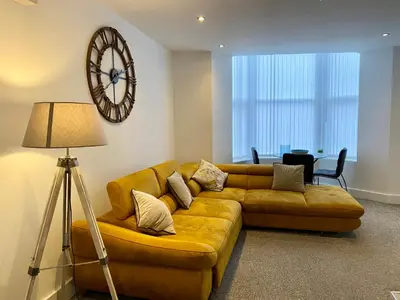a living room with a couch and a clock on the wall at Winter Gardens Service Apartments by Blackpool Service Apartments in Blackpool