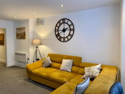 a living room with a couch and a clock on the wall at Winter Gardens Service Apartments by Blackpool Service Apartments in Blackpool