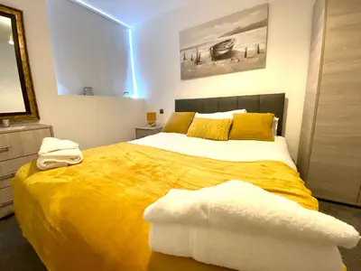 a bedroom with a large bed with a yellow blanket at Winter Gardens Service Apartments by Blackpool Service Apartments in Blackpool