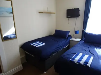 two beds in a small room with a mirror at Glendowie Hotel in Blackpool