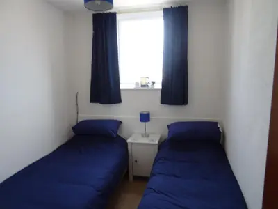 two beds in a room with blue pillows and a window at Glendowie Hotel in Blackpool