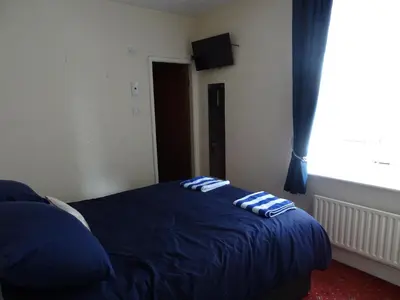 a bedroom with a bed with blue sheets and a window at Glendowie Hotel in Blackpool