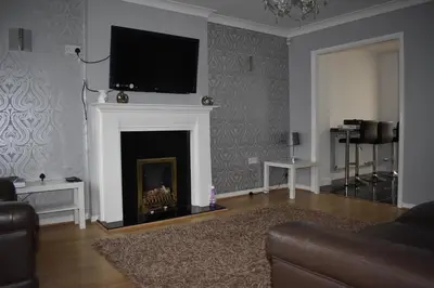 a living room with a fireplace with a tv above it at Redwood House in Liverpool