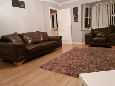 a living room with a leather couch and a rug at Redwood House in Liverpool