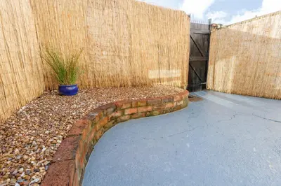 a garden with a brick retaining wall and a fence at Sapphire Home Stay in Liverpool