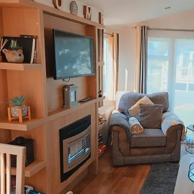 a living room with a television and a chair at Rydal 38 Haven lakeland LA11 7LT in Flookburgh