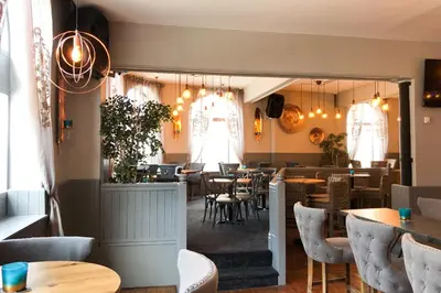 a restaurant with tables and chairs and lights at The Derby Hotel in Barrow in Furness
