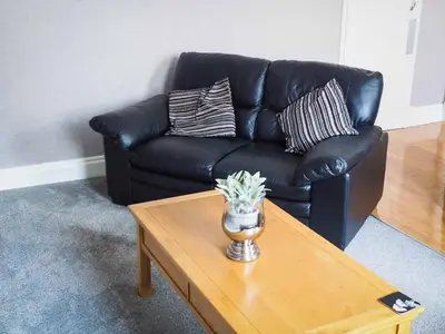 a black leather couch in a living room with a coffee table at The Derby Hotel in Barrow in Furness