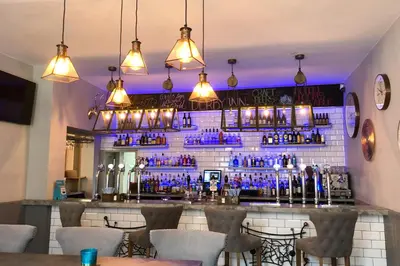 a bar with blue bottles on a brick wall at The Derby Hotel in Barrow in Furness
