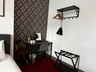 a bedroom with a bed and a desk with a chair at The Derby Hotel in Barrow in Furness