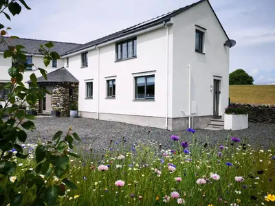 a white house with flowers in front of it at Yew Fold in Soutergate