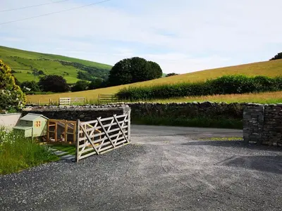 a wooden gate in a field with a stone wall at Yew Fold in Soutergate