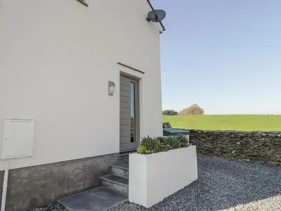 a white house with stairs and a stone wall at Yew Fold in Soutergate