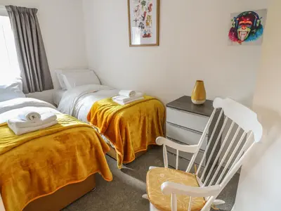 a bedroom with two twin beds and a chair at Ellie's Lodge in Ulverston