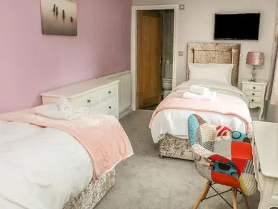 a bedroom with two beds and a chair and a television at Ellie's Lodge in Ulverston