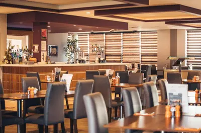 a restaurant with tables and chairs and a bar at Blackpool Football Club Stadium Hotel, a member of Radisson Individuals in Blackpool