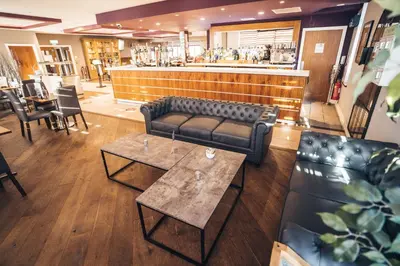 a restaurant with a couch and tables and a bar at Blackpool Football Club Stadium Hotel, a member of Radisson Individuals in Blackpool