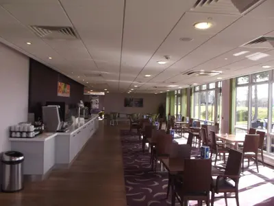 a dining room with tables and chairs and windows at Holiday Inn Express Preston South by IHG in Preston