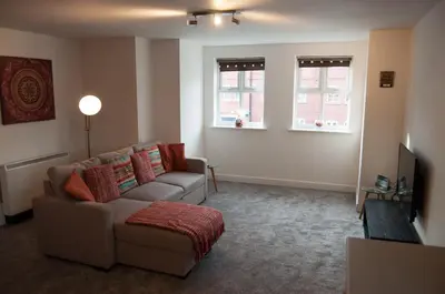 a living room with a couch and two windows at Bolton Executive Apartment in Bolton