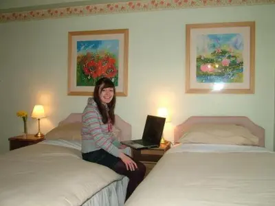 a woman sitting on a bed in a hotel room at Somerset House B&B in Grange Over Sands