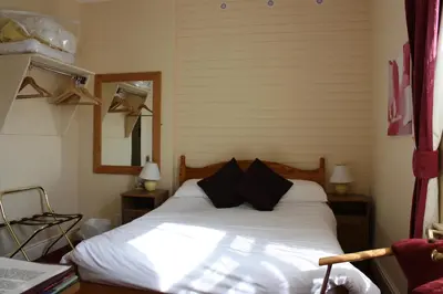 a bedroom with a bed with white sheets and black pillows at Somerset House B&B in Grange Over Sands
