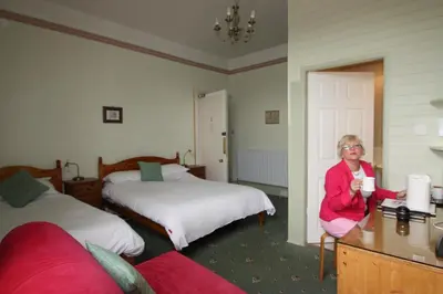 a woman sitting in a room with two beds at Somerset House B&B in Grange Over Sands