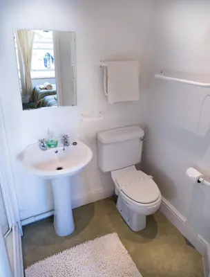 a white bathroom with a toilet and a sink at Somerset House B&B in Grange Over Sands
