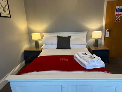 a bedroom with a bed with two lamps and towels on it at The Hinds Head Hotel in Chorley