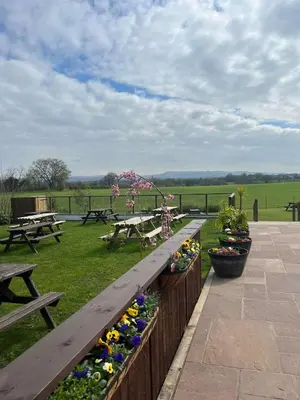 a wooden bench with flowers in a park at The Hinds Head Hotel in Chorley