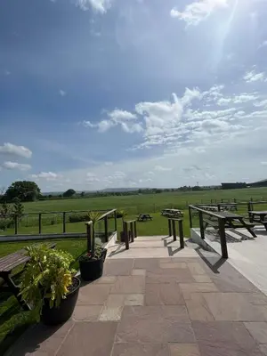 a patio with picnic tables and a view of a field at The Hinds Head Hotel in Chorley