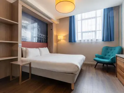 a hotel room with a bed and a blue chair at Aparthotel Adagio Liverpool City Centre in Liverpool