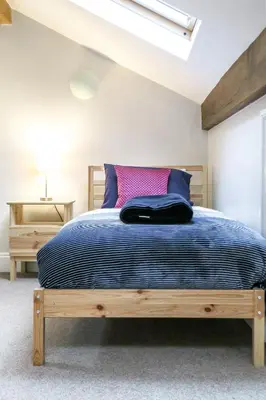 a bedroom with a bed with a blue comforter at Bedzzz - Booklovers Dream in Preston